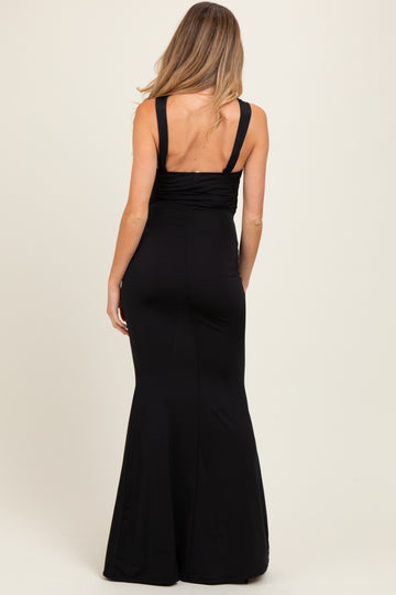 woman wearing a black maternity dress with a fitted silhouette and flared bottom, shown from the back