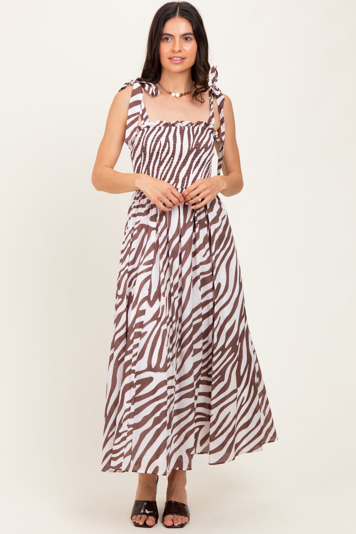 woman wearing a brown and white striped maxi dress with tie shoulder straps and a smocked bodice
