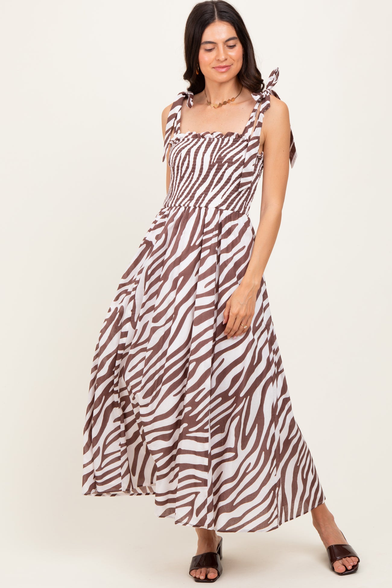 woman wearing a brown and white zebra print maxi dress with tie straps and a smocked bodice
