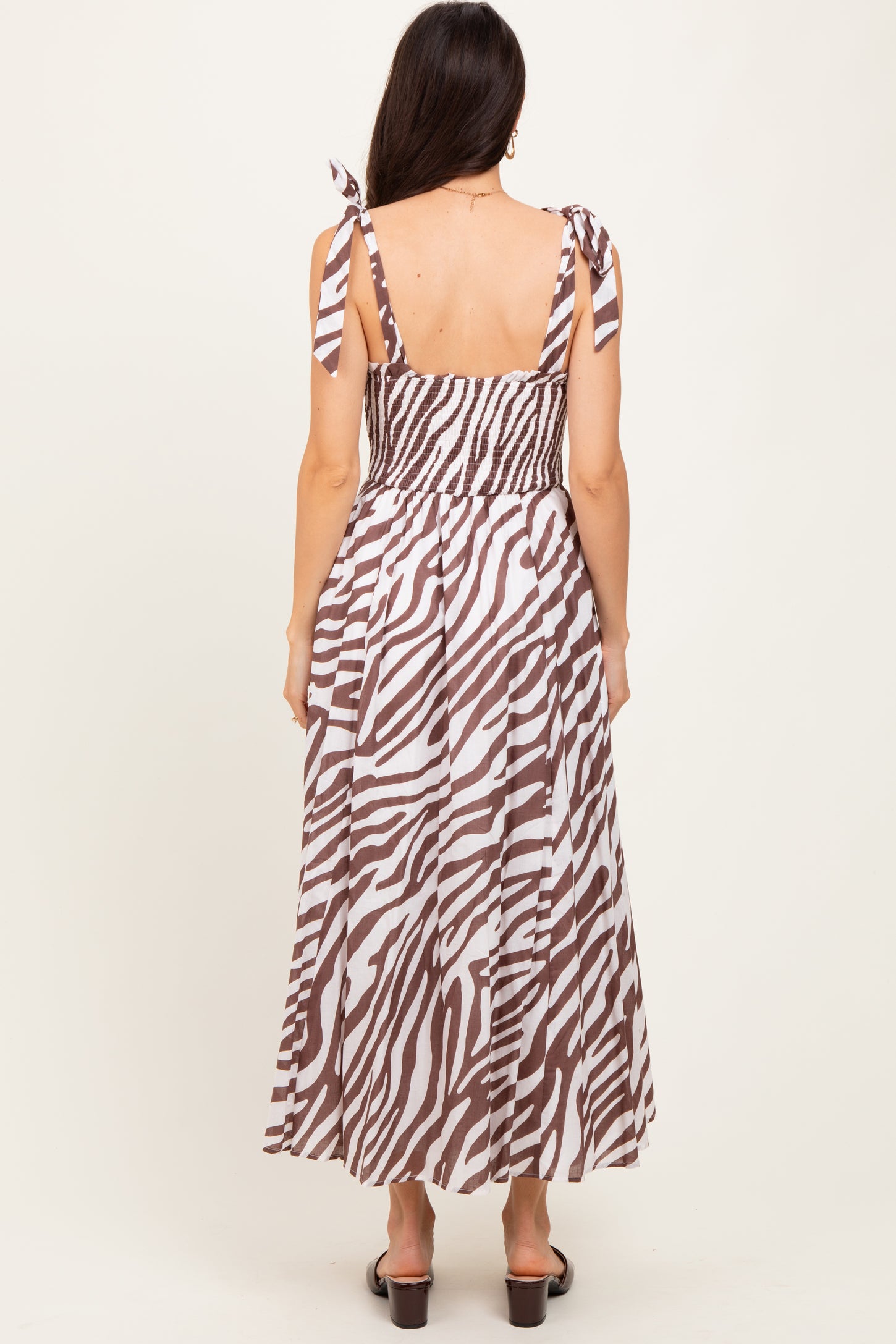woman wearing a brown and white zebra print maxi dress with adjustable tie straps and a smocked back design