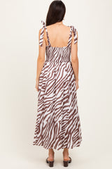 woman wearing a brown and white zebra print maxi dress with adjustable tie straps and a smocked back design