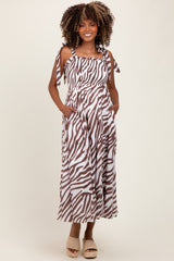 woman wearing a brown and white zebra print maternity maxi dress with pockets and tie straps, showing a baby bump