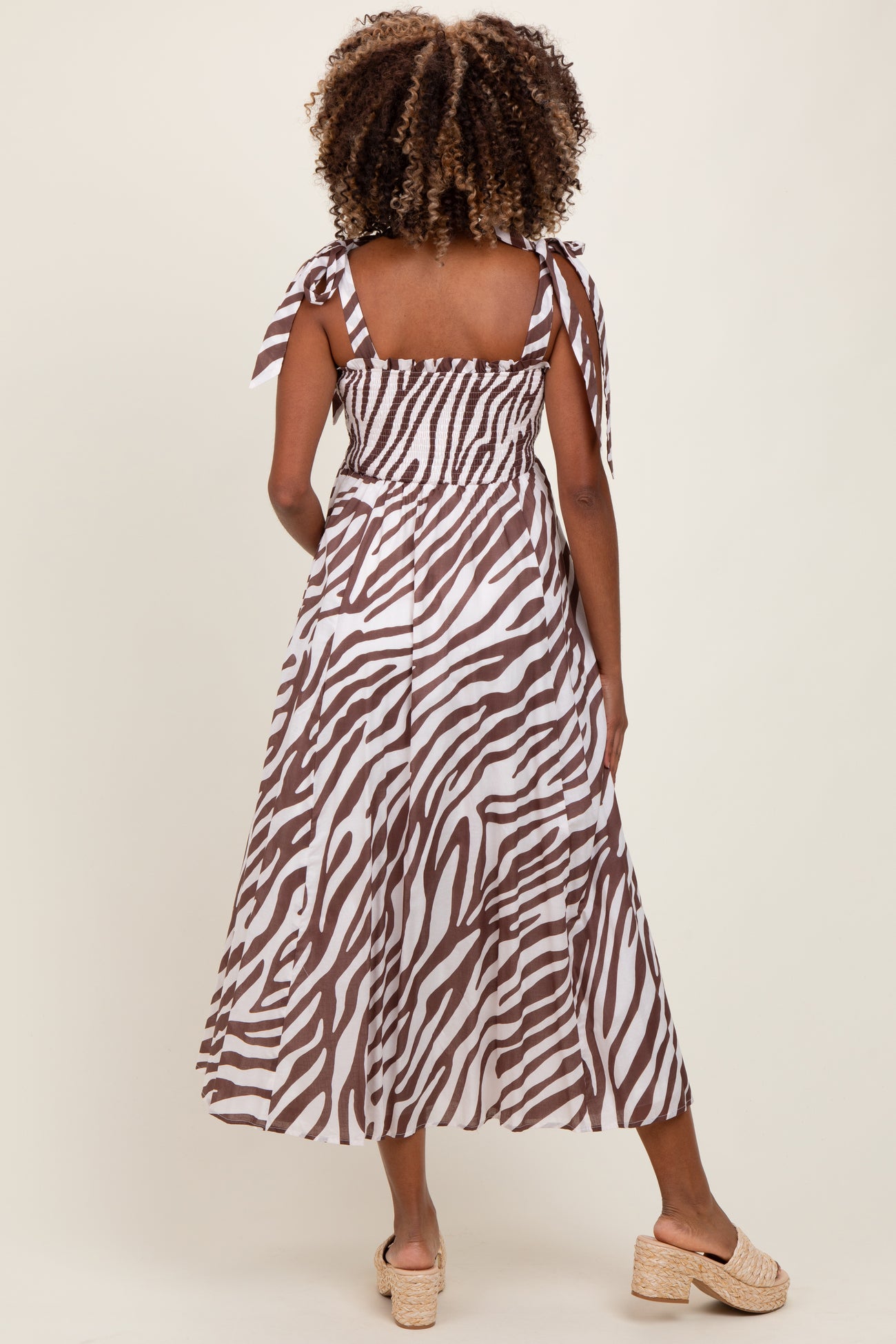 woman wearing a brown and white zebra print maternity midi dress with tie straps and a smocked back