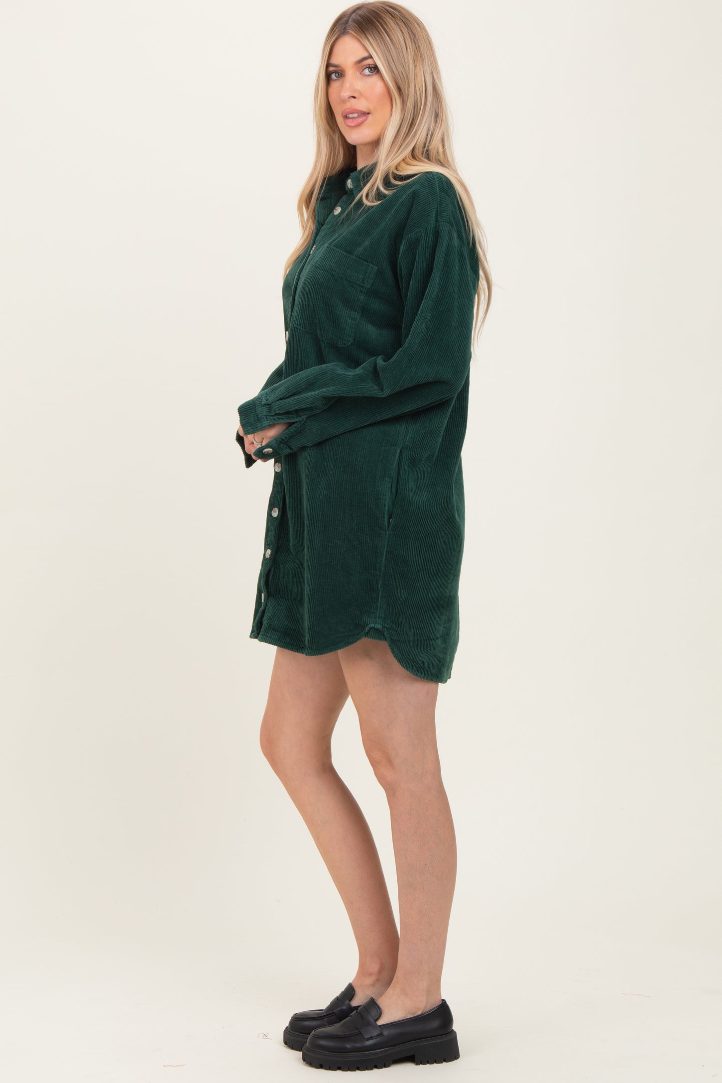 woman wearing a dark green corduroy shirt dress with a button-up front and long sleeves