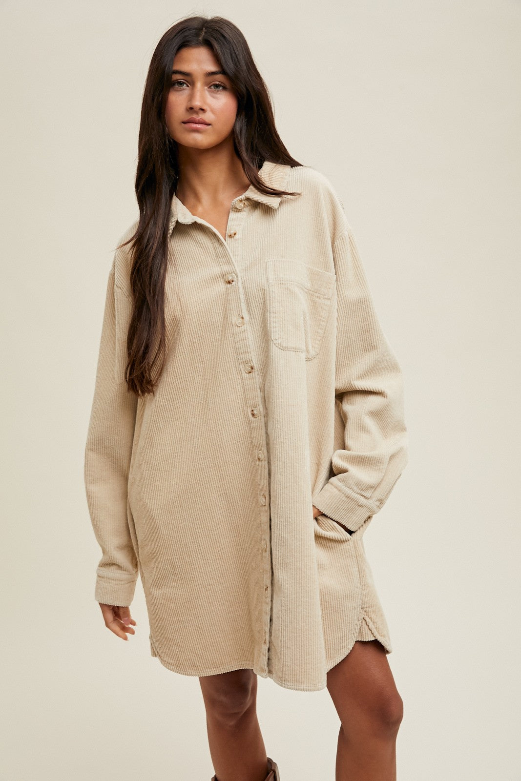 woman wearing a beige corduroy shirt dress with a front pocket and button-down closure