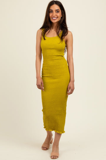 woman wearing a mustard yellow fitted midi dress with ruching and ruffle hem details
