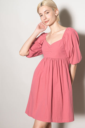 woman wearing a pink short puff sleeve dress with a square neckline and a fitted bodice