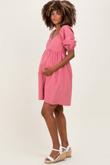 woman wearing a pink puff sleeve maternity dress and holding her baby bump