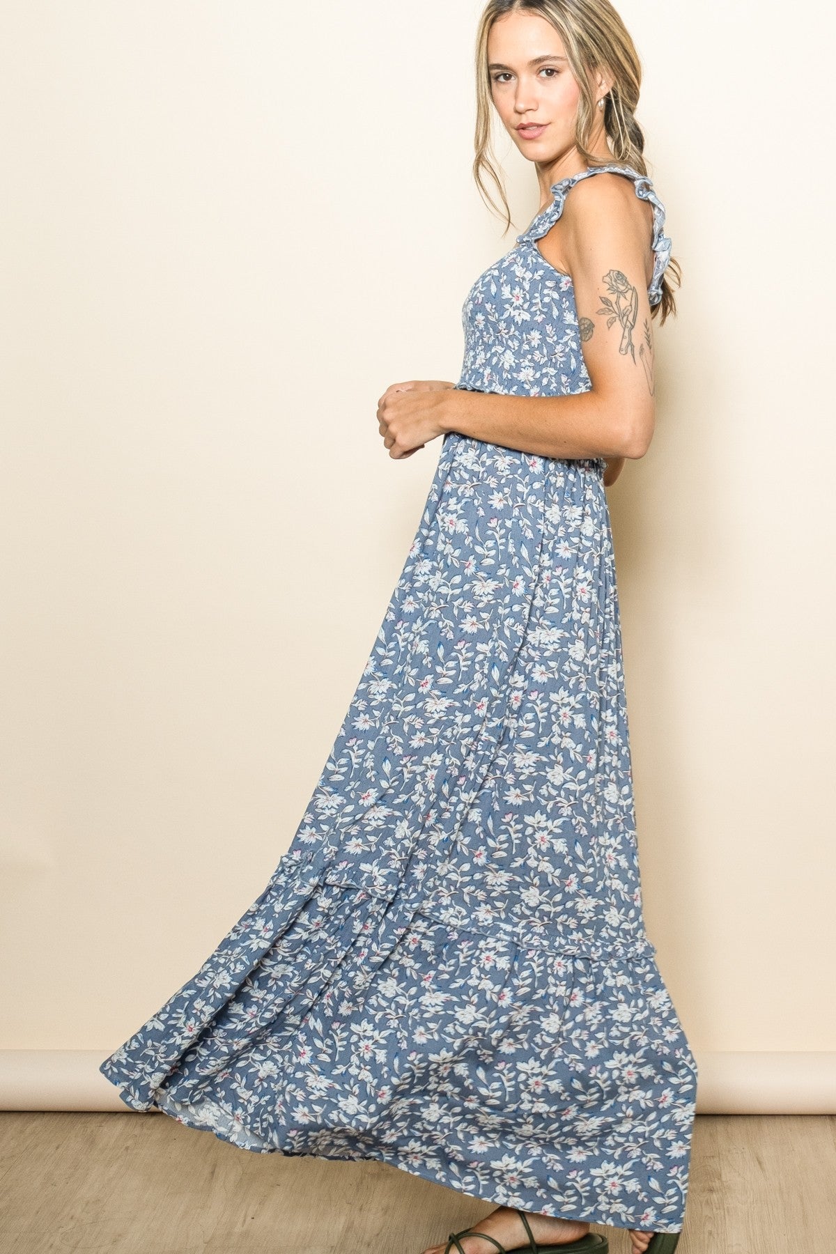 woman wearing a blue floral maxi dress with ruffled straps and flowing skirt