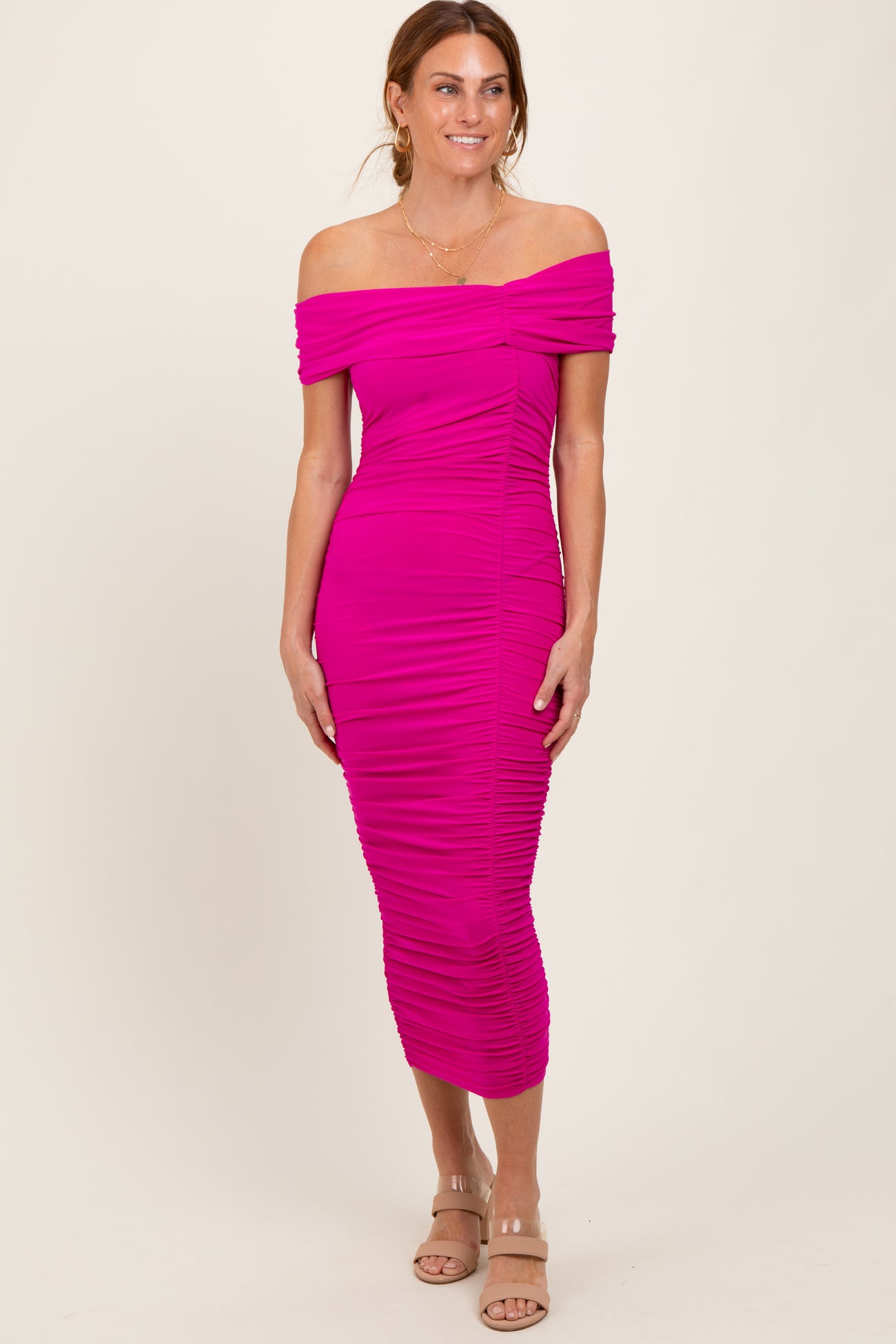 woman wearing a bright pink off-the-shoulder midi dress with ruching details and a form-fitting silhouette