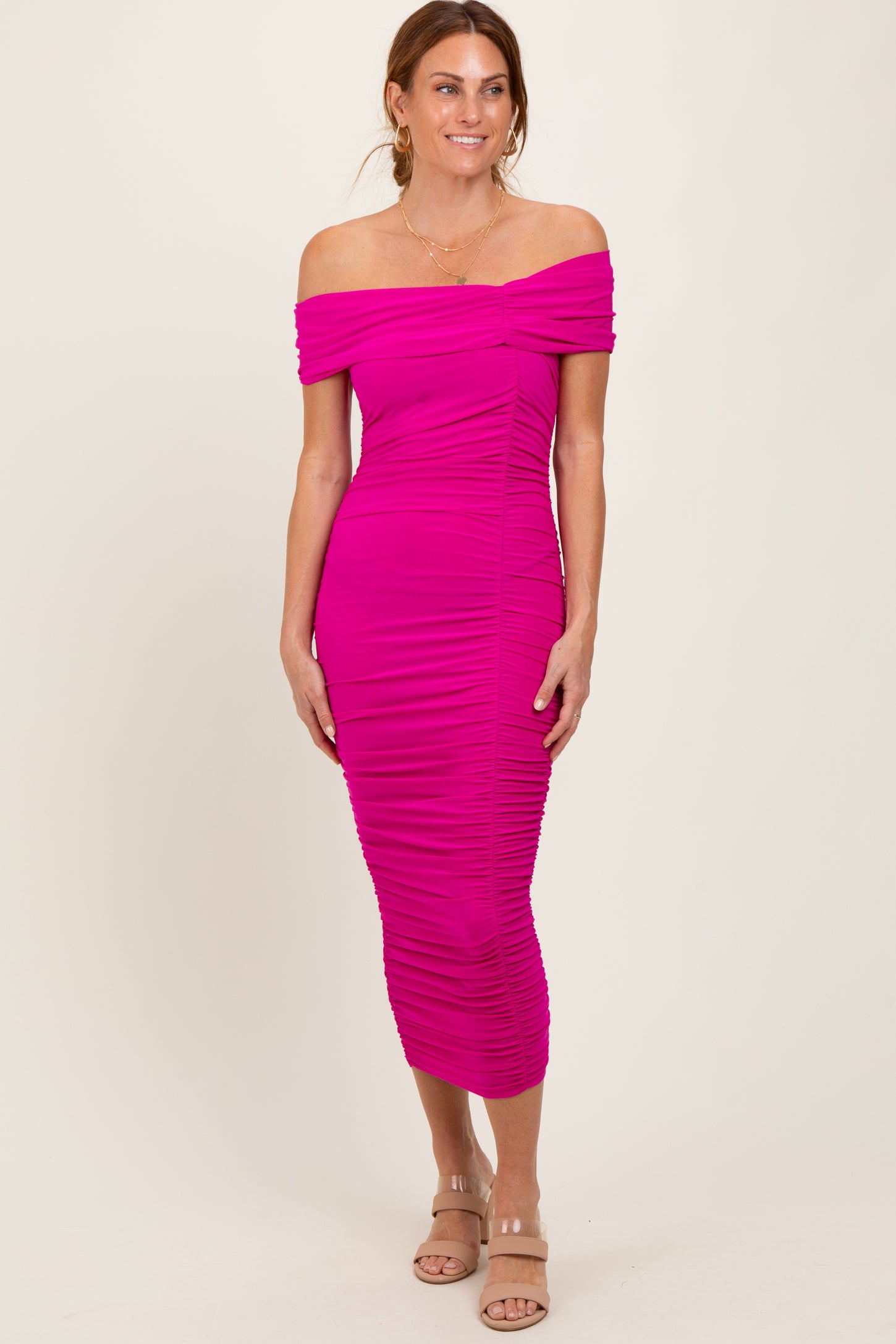 woman wearing a bright pink off-the-shoulder midi dress with ruching details and a form-fitting silhouette