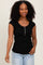 woman wearing a black ribbed scoop neck top with cap sleeves and button details, paired with light blue jeans