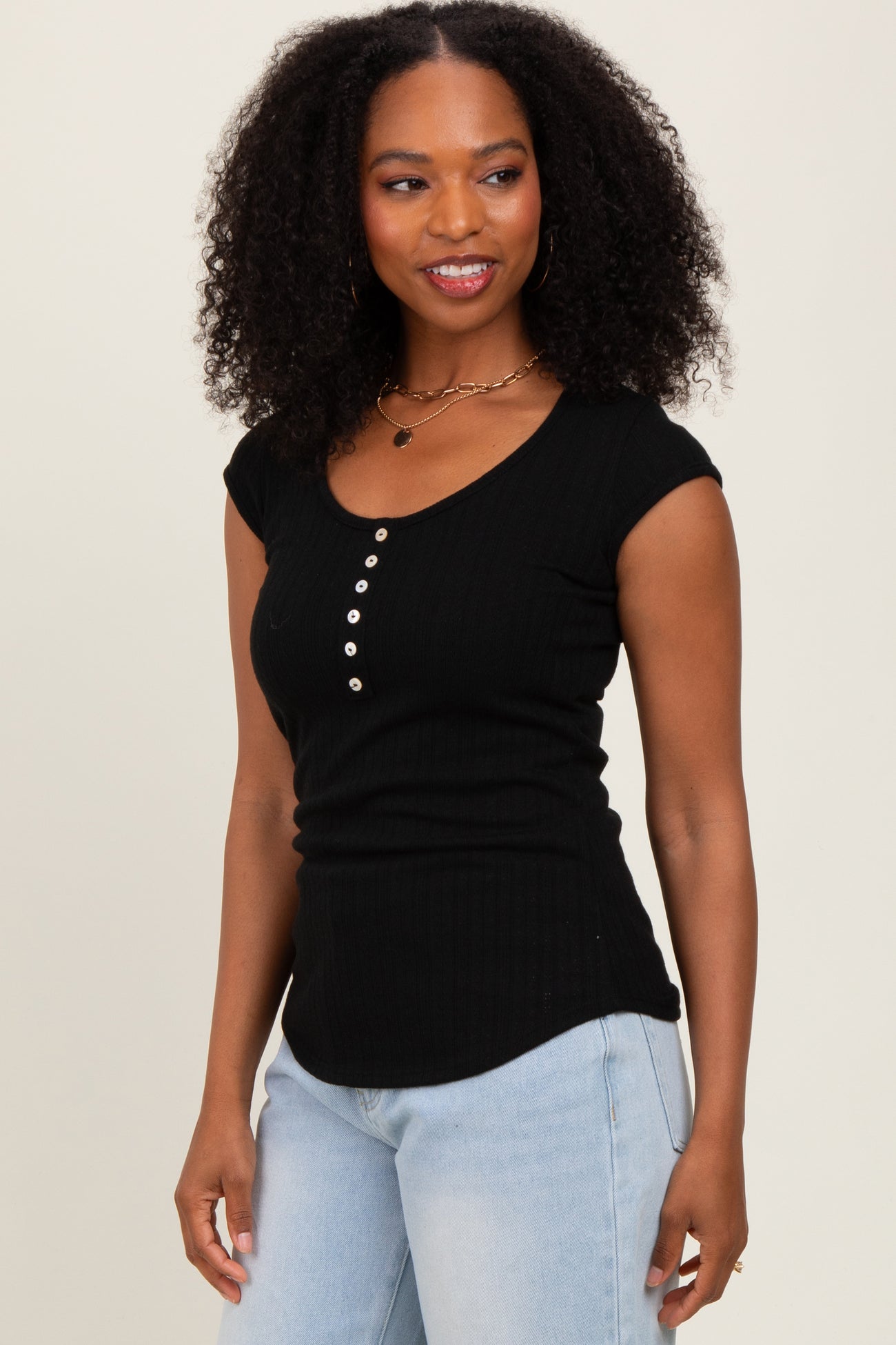 woman wearing a black short sleeve ribbed henley top with button details and smiling at the camera