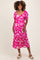 woman wearing a pink floral maternity dress with puff sleeves and a tiered skirt, showing her baby bump