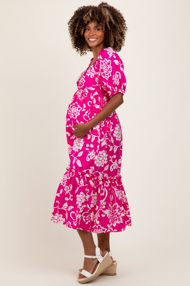 woman wearing a pink floral maternity dress and holding her baby bump