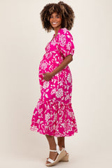 woman wearing a pink floral maternity dress and holding her baby bump