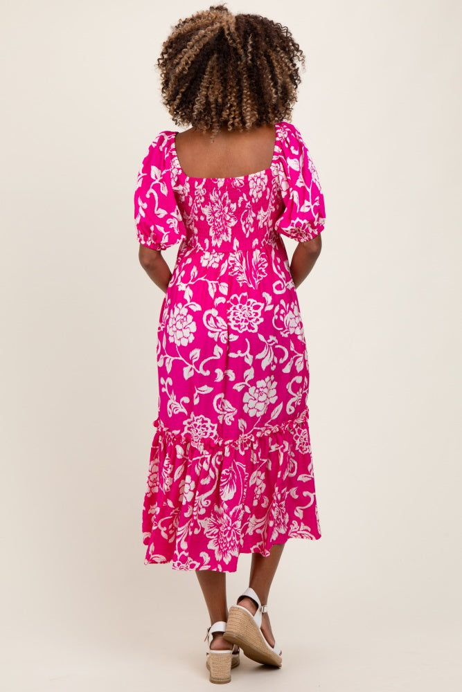 woman wearing a pink floral print maternity dress with puff sleeves and a ruffled hem, showing a baby bump