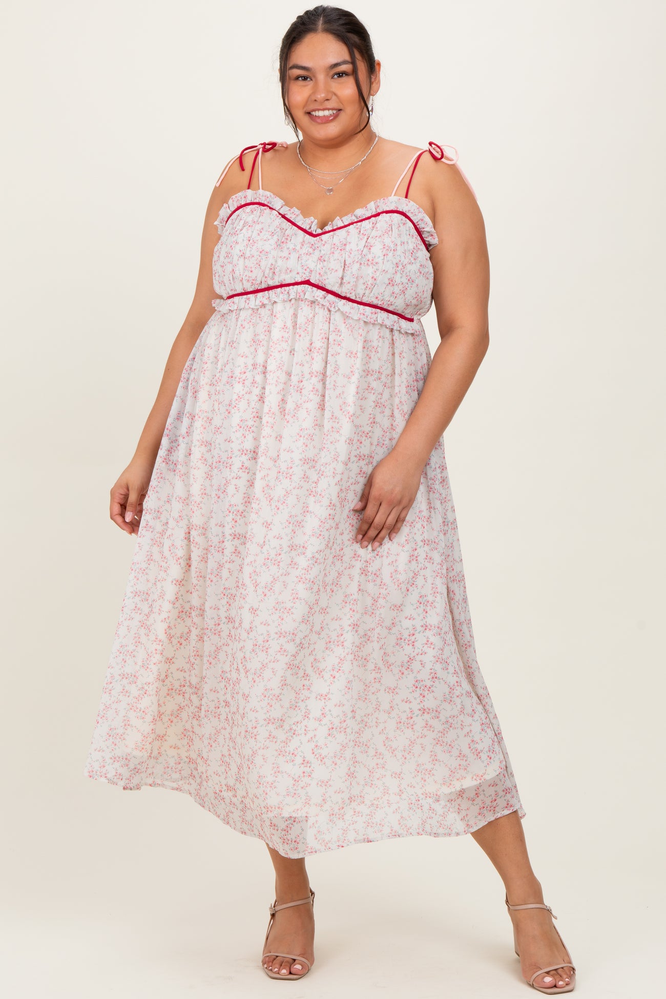 plus size woman wearing a white floral maxi dress with pink ruffles and tie straps