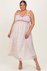 plus size woman wearing a white floral maxi dress with pink ruffles and tie straps
