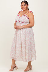 woman wearing a white floral plus-size maxi dress with red accents and adjustable tie straps