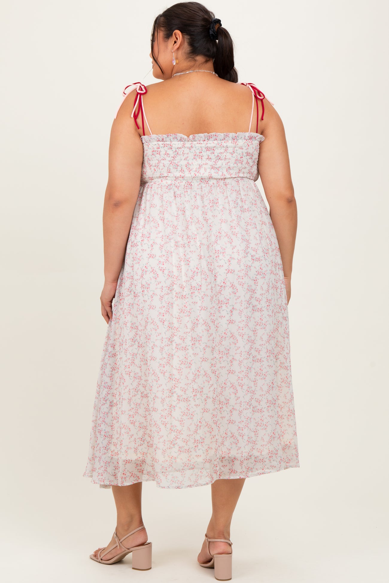woman wearing a back view of a white floral midi dress with pink straps and a smocked bodice in women's plus size