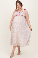 woman wearing a floral print maternity plus maxi dress with red accents and a visible baby bump