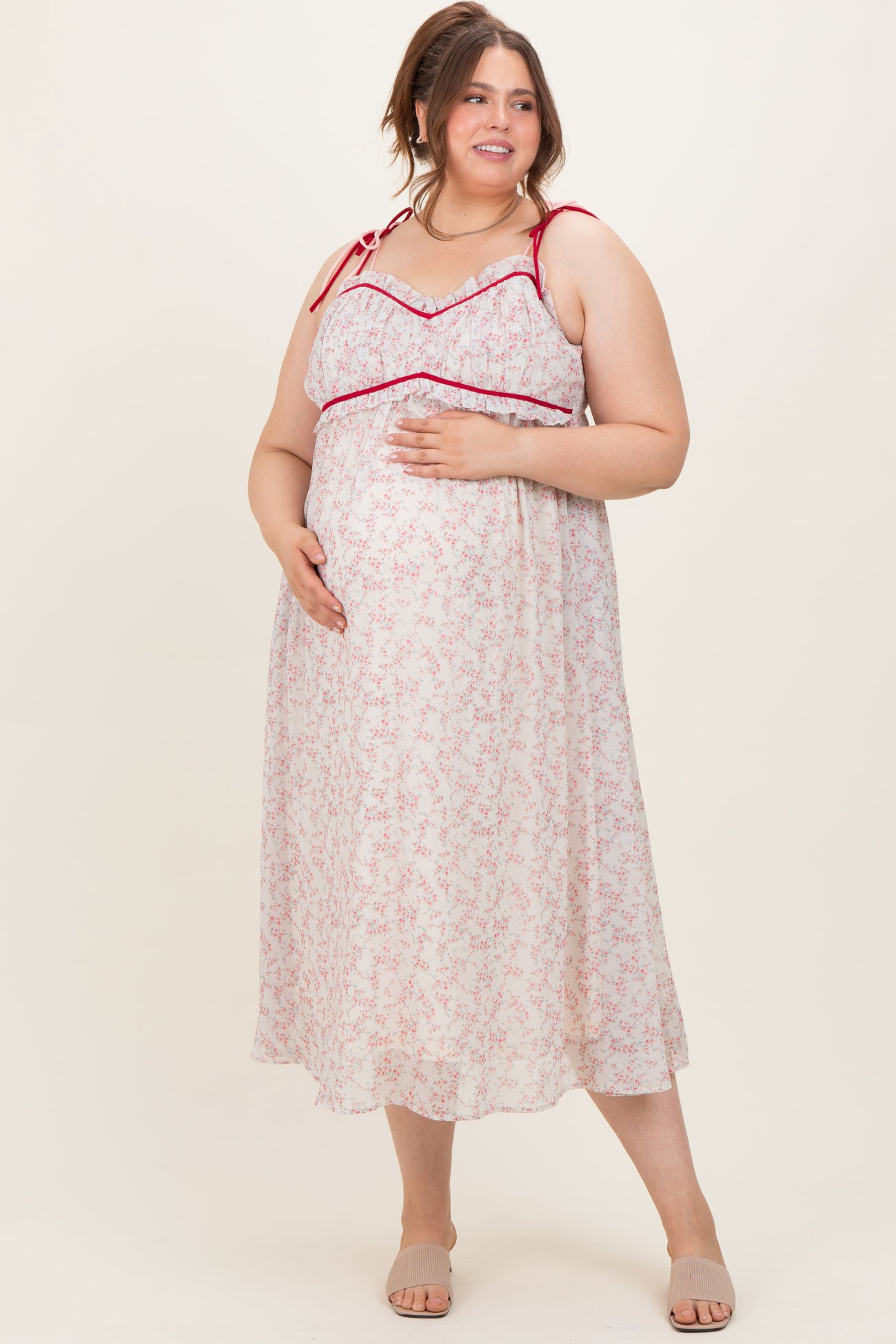 woman wearing a white floral maternity dress with red accents and a visible baby bump