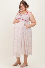 woman wearing a floral sleeveless maternity dress with red straps and pockets, showing her baby bump