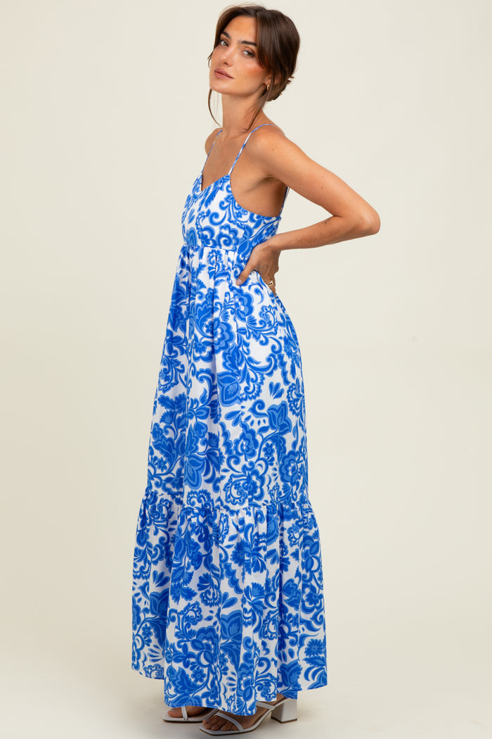 woman wearing a blue and white floral maxi dress with a tiered skirt and spaghetti straps