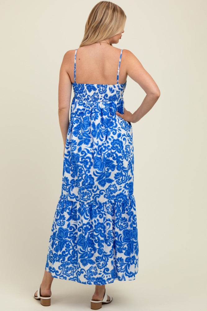 woman wearing a blue and white floral print maternity maxi dress with adjustable straps and a flowing skirt