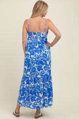 woman wearing a blue and white floral print maternity maxi dress with adjustable straps and a flowing skirt