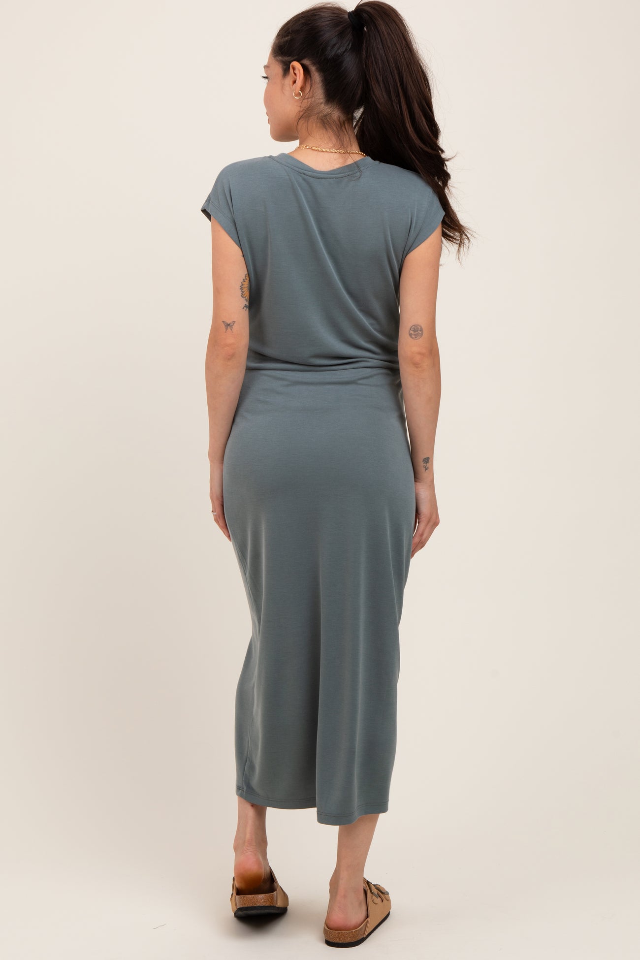 woman wearing a gray maternity maxi dress with cap sleeves and a form-fitting silhouette, showing a baby bump