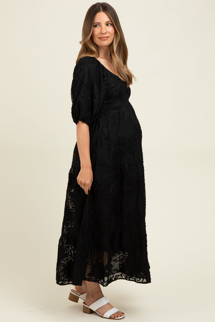 woman wearing a black floral lace maternity maxi dress and showcasing her baby bump