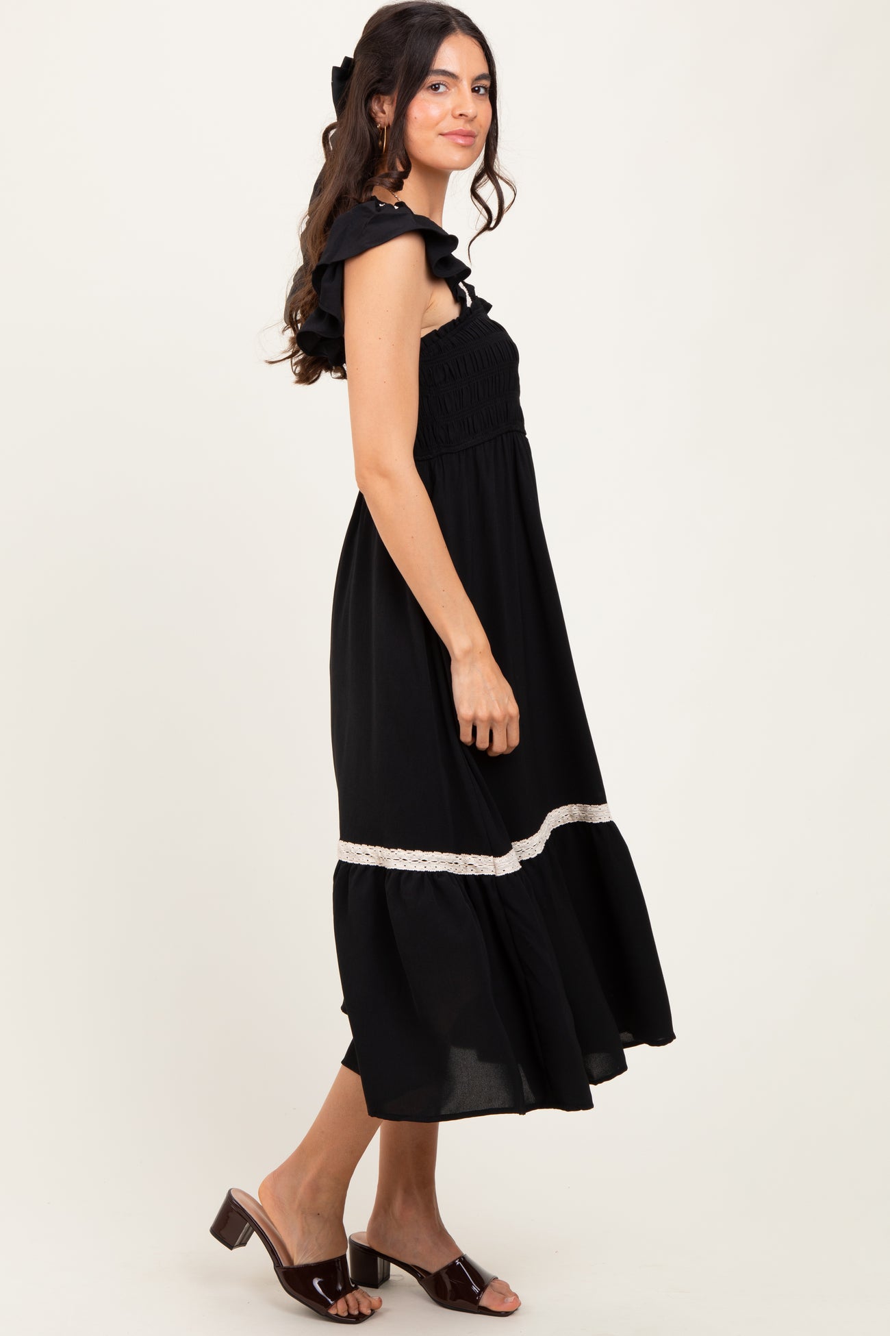 woman wearing a black off-shoulder maxi dress with ruffled sleeves and a lace trim at the hem