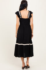 woman wearing a black midi dress with ruffled straps and a smocked bodice, seen from the back