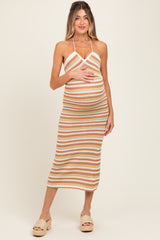 woman wearing a striped tan and white halter neck maternity dress, holding her baby bump