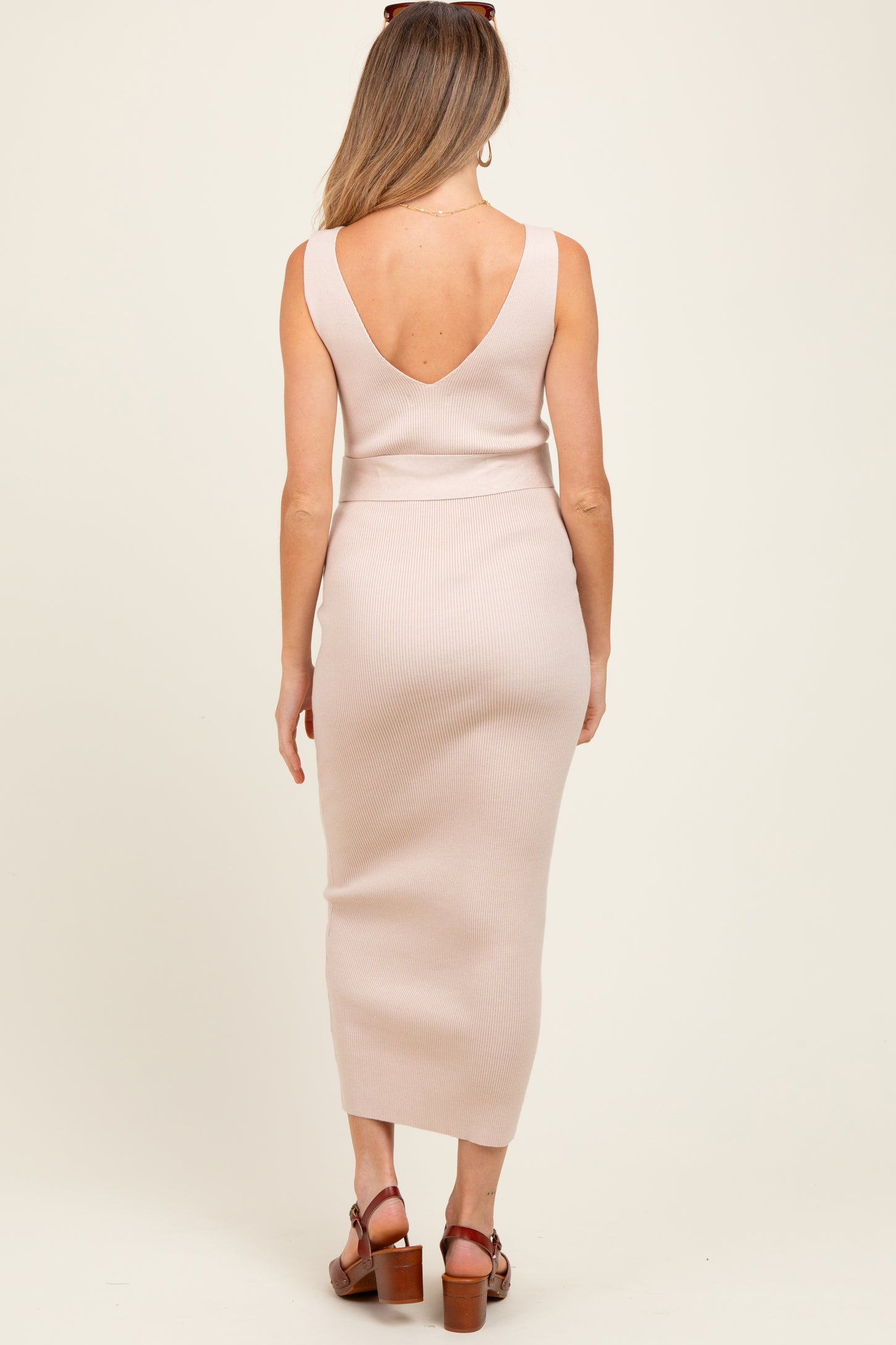 woman wearing a light pink ribbed maternity dress with a deep v-back and long skirt