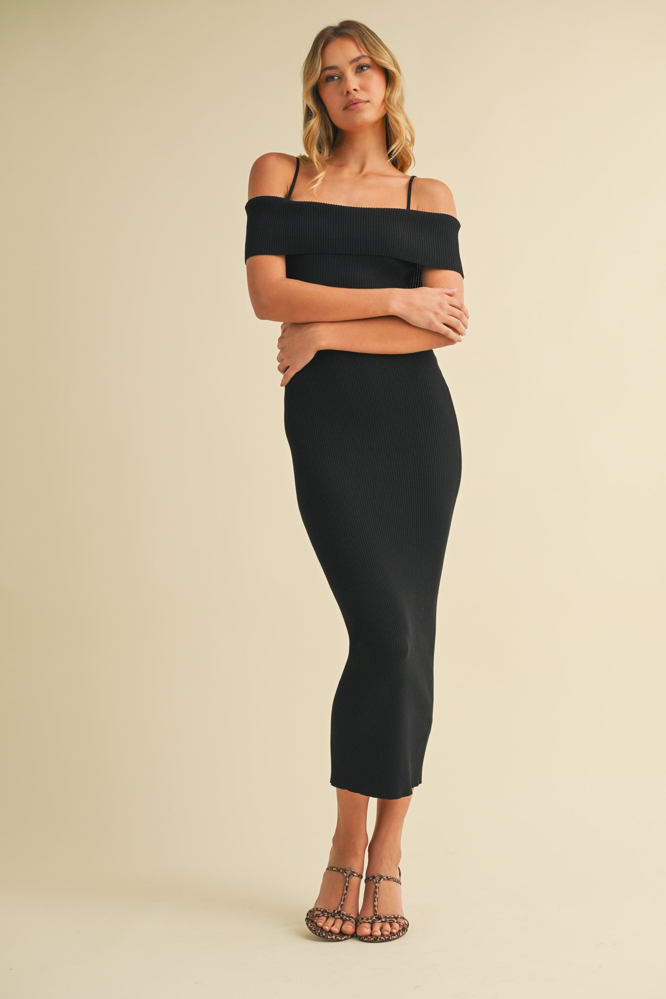woman wearing a black ribbed off-the-shoulder midi dress with spaghetti straps and strappy heels