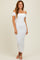 woman wearing a white off-the-shoulder ribbed maxi dress with fitted silhouette and side slit