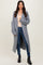 woman wearing a long grey ribbed cardigan over a beige top and blue jeans, paired with black ankle boots