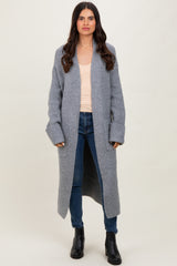 woman wearing a long gray ribbed cardigan over a light peach tank top and blue jeans