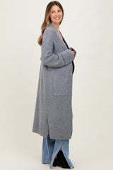 woman wearing a long gray knitted maternity cardigan over a black top, with visible baby bump and relaxed fit jeans
