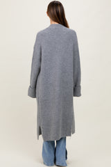 woman wearing a long grey maternity cardigan with ribbed texture and side slits, viewed from the back