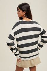 woman wearing a black and white striped oversized sweater with long sleeves, styled with a beige skirt