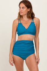 woman wearing a teal scalloped edge bikini top and high-waisted bikini bottom
