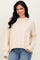 woman wearing a cream oversized sweater with ribbed texture and side slits, paired with blue jeans