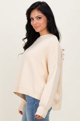 woman wearing a soft beige oversized sweater with a relaxed fit and long sleeves paired with light blue jeans