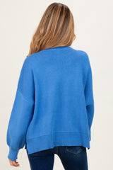 woman wearing a soft blue oversized maternity sweater with long sleeves and a relaxed fit