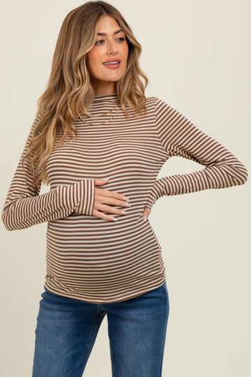 woman wearing a brown and cream striped long sleeve maternity top and holding her baby bump