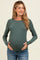 woman wearing a dark green ribbed long sleeve maternity top and holding her baby bump